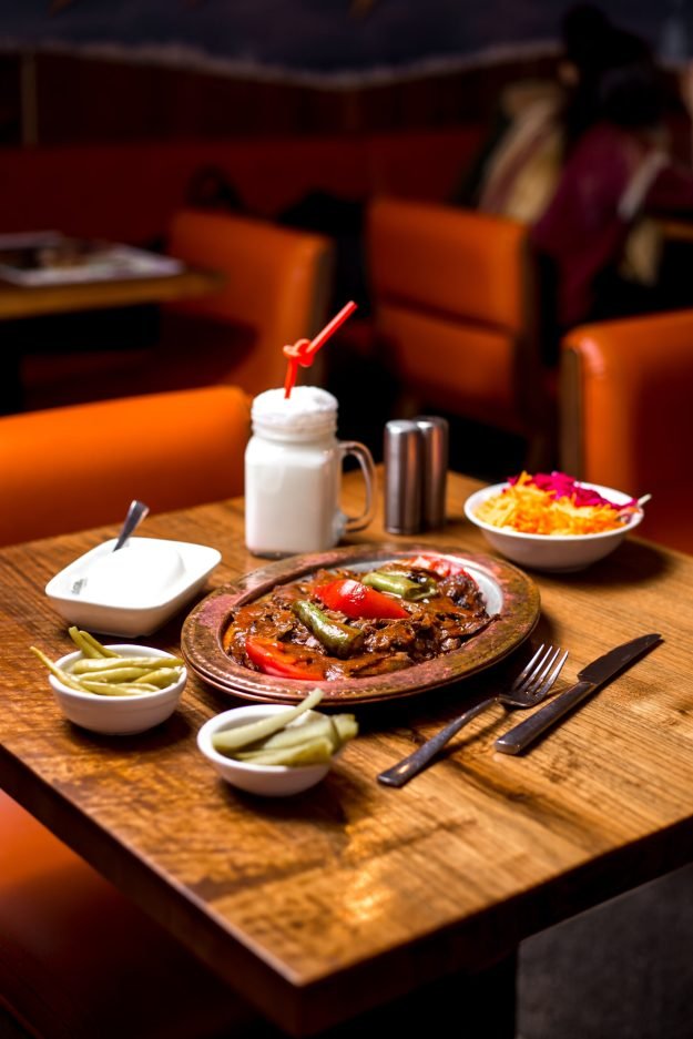 iskender kebab in copper serving served with pickles yogurt and ayran